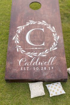 a personalized cornhole board is laying on the grass next to some pillows and napkins