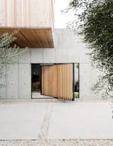 an open door on the side of a building next to a tree and shrubbery