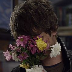 a man holding flowers in his face