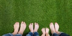 four people standing in the grass with their feet up