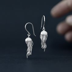 Get caught up in the tentacles of our little jellyfish.  Earrings made in sterling silver with a matte, sandblasted finish.  This design of dangling earrings has a total length of 4 centimeters and the diameter of the jellyfish head is 0.8 millimeters.  Don't hesitate and show off these fantastic jellyfish in your daily life. Our designs have handmade finishes, so measurements may vary slightly. Jellyfish Ring, Jellyfish Earrings Diy, Concrete Jellyfish Earrings, Jellyfish Earring, Silver Ocean-inspired Earrings, Jellyfish Jewelry, Jellyfish Earrings, Marine Animals, Dangling Earrings