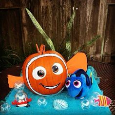 an orange and blue pumpkin sitting on top of a table next to a fish statue