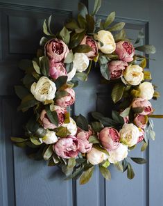 a wreath with pink and white flowers hanging on a door