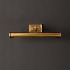 an old fashioned brass toilet roll holder on a gray wall with a black back ground