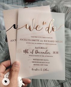 a person holding up two wedding cards with the word we do written on them in gold foil