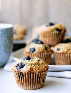 blueberry muffins on a white plate with a cup of coffee in the background