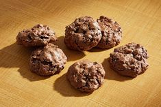 four chocolate cookies sitting on top of a wooden table