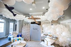 a room filled with lots of white balloons and an airplane hanging from the ceiling above it