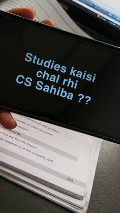 a person holding up a cell phone with the text studies kasi chal rih cs sahiba?