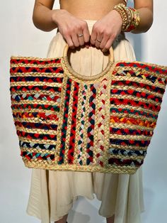 a woman holding a multicolored woven purse