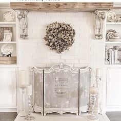 a white fireplace with a wreath on the wall above it and candles in front of it