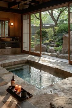 an indoor hot tub with two candles on the side and some rocks in front of it