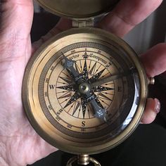 a person holding an old fashioned compass in their left hand with both hands on it