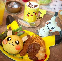 a yellow plate topped with lots of food next to two stuffed animals on top of a wooden table