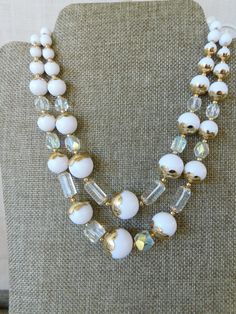 Gorgeous double strand white plastic necklace with aurora borealis glass beads. Gold tone accents...scalloped bead covers and spacer beads. Shortest strand is 10", longer strand is 12" and the necklace has a 3" extension. Clean and is in beautiful condition. SHIPS TO US LOCALES/MEXICO/CANADA/AUSTRALIA & NZ ONLY. White Double Strand Jewelry For Anniversary, White Faceted Bead Wedding Necklace, White Jewelry With Spacer And Round Beads, White Faceted Beads For Wedding, White Faceted Beads Round Jewelry, White Jewelry With Round Spacer Beads, White Faceted Beads Necklace For Wedding, White Wedding Beads Necklace With Faceted Beads, Vintage Double Strand White Jewelry