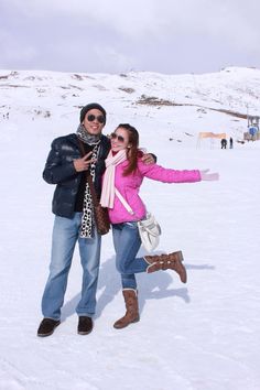 two people standing in the snow with their arms out and one person holding her hand out