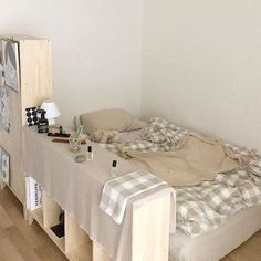 an unmade bed sitting on top of a hard wood floor next to a white wall