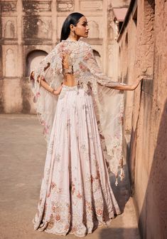 Presenting an off-white Chikankari mukaish lehenga adorned with pearl and zardozi hand embroidery. Paired seamlessly with a sheeted crystal bustier choli and an organza cutwork border-embroidered dupatta. This ensemble exudes timeless elegance, combining traditional craftsmanship with modern flair. Traditional Embroidered Pre-draped Saree With Cape Sleeves, Embroidered Choli With Cape Sleeves For Reception, Traditional Embroidered Anarkali Set With Cape Sleeves, Bollywood Embroidered Palazzo Set With Cape Sleeves, Designer Dresses With Intricate Embroidery And Cape Sleeves, Fitted Gown With Dupatta And Cape Sleeves, Anarkali Pre-draped Saree With Zari Work And Cape Sleeves, Anarkali Pre-draped Saree With Sheer Dupatta And Cape Sleeves, Fitted Embroidered Anarkali Set With Cape Sleeves