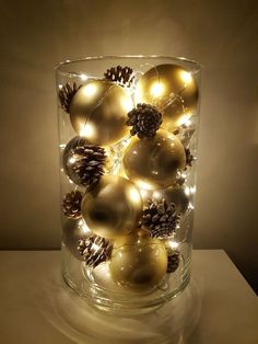 a glass vase filled with christmas ornaments on top of a table