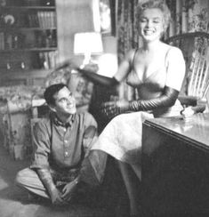 an old black and white photo of a woman sitting on a chair next to a man