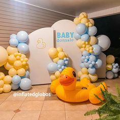 an inflatable rubber ducky is sitting on the floor next to balloons