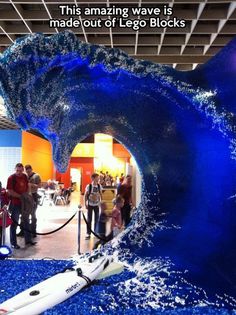 people are standing in front of a fake wave inside an office building that is blue and white