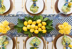 the table is set with lemons and blue napkins, yellow flowers, and white plates