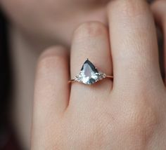 a woman's hand holding an engagement ring with two pear shaped diamonds on it