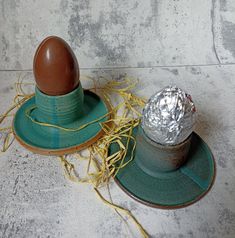 an egg sitting on top of a green plate next to a tin foil covered cup