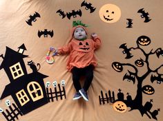 a baby laying on top of a bed covered in halloween decorations