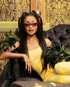 a woman with long hair and sunglasses sitting on a couch holding plants in her hands