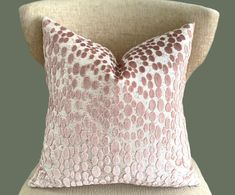 a pink and white pillow sitting on top of a chair