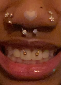 a close up of a person's smile with piercings on their nose and teeth