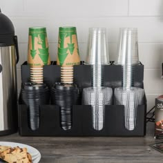 there are many cups that are on the counter next to some cookies and other items