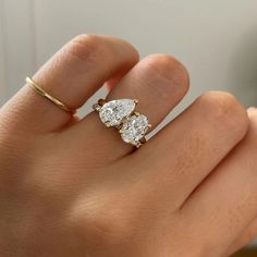 a woman's hand with two pear shaped diamond rings on top of her finger