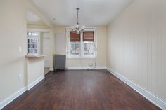 an empty living room with hard wood flooring and white paint on the walls, along with a radiator