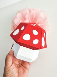 a hand holding a red and white dice with pink tissue paper on it's side