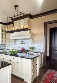 a kitchen with white cabinets and black counter tops, an island in the middle has candles on it