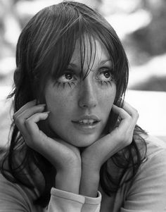 a black and white photo of a woman with freckles on her face looking at the camera