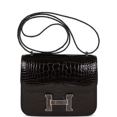 This rare Hermes Constance 18, is of Black shiny alligator with palladium and tiger's eye hardware and features tonal stitching, a "H" snap lock closure, and an adjustable shoulder strap.The interior is lined with black lambskin and has an open pocket on the front wall, a center divide, and a slit pocket on the back wall. Collection: UOrigin: FranceCondition: Pristine, new or never (Plastic on hardware)Accompanied by: Hermes box, Hermes dustbag, felt and CITESMeasurements: 7.25" width x 6.25" height x 2.25" depth; 10" double; 20" single Front Wall, Snap Lock, Hermes Box, Hermes Constance, Hermes Handbags, Tiger's Eye, New Bag, Tiger Eye, Wallet Case