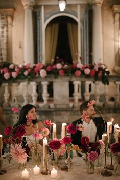 a man and woman sitting at a table surrounded by candles