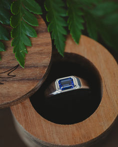 A men's engagement ring from Staghead Designs sits in a wooden ring box surrounded by fern leaves. This 14K white gold ring in our "Arthur" design features a half bezel set emerald cut lab-grown blue sapphire. Whiskey Barrel Wedding Ring, Mens Sapphire Ring, Antler Wedding Rings, Handcrafted Engagement Ring, Wood Wedding Ring, Sapphire Wedding Band, Wedding Clothing, Wedding Rings Rose Gold, Sapphire Wedding