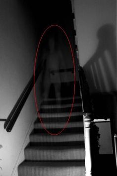 the shadow of a person walking down a set of stairs in front of a door