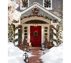 a red door is decorated with christmas wreaths and lights in front of a house