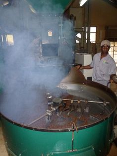 a man standing in front of a large pot filled with steam coming out of it