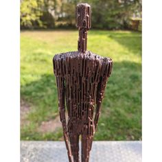 a metal sculpture sitting on top of a cement slab next to a grass covered field