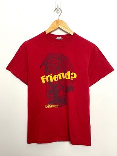 a red t - shirt with the word friend on it hanging from a wooden hanger