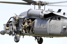 an army helicopter flying through the air with soldiers inside