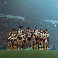 a group of rugby players huddle together on the field in front of an audience