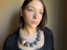 a woman wearing a black sweater and a necklace with beads on it's neck